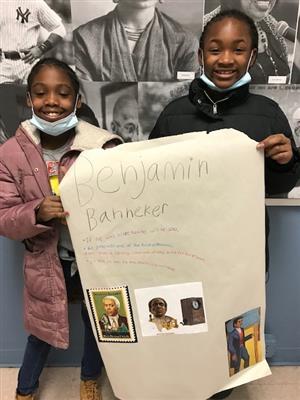 Photo of two Lincoln students holding a poster with information and photos about Benjamin Banneker.